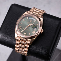 Thumbnail for Rolex Day-Date 40mm 18K Everose Gold Olive Green Roman Dial Fluted Bezel President Bracelet (Ref 228235) - front view on a black leather display stand