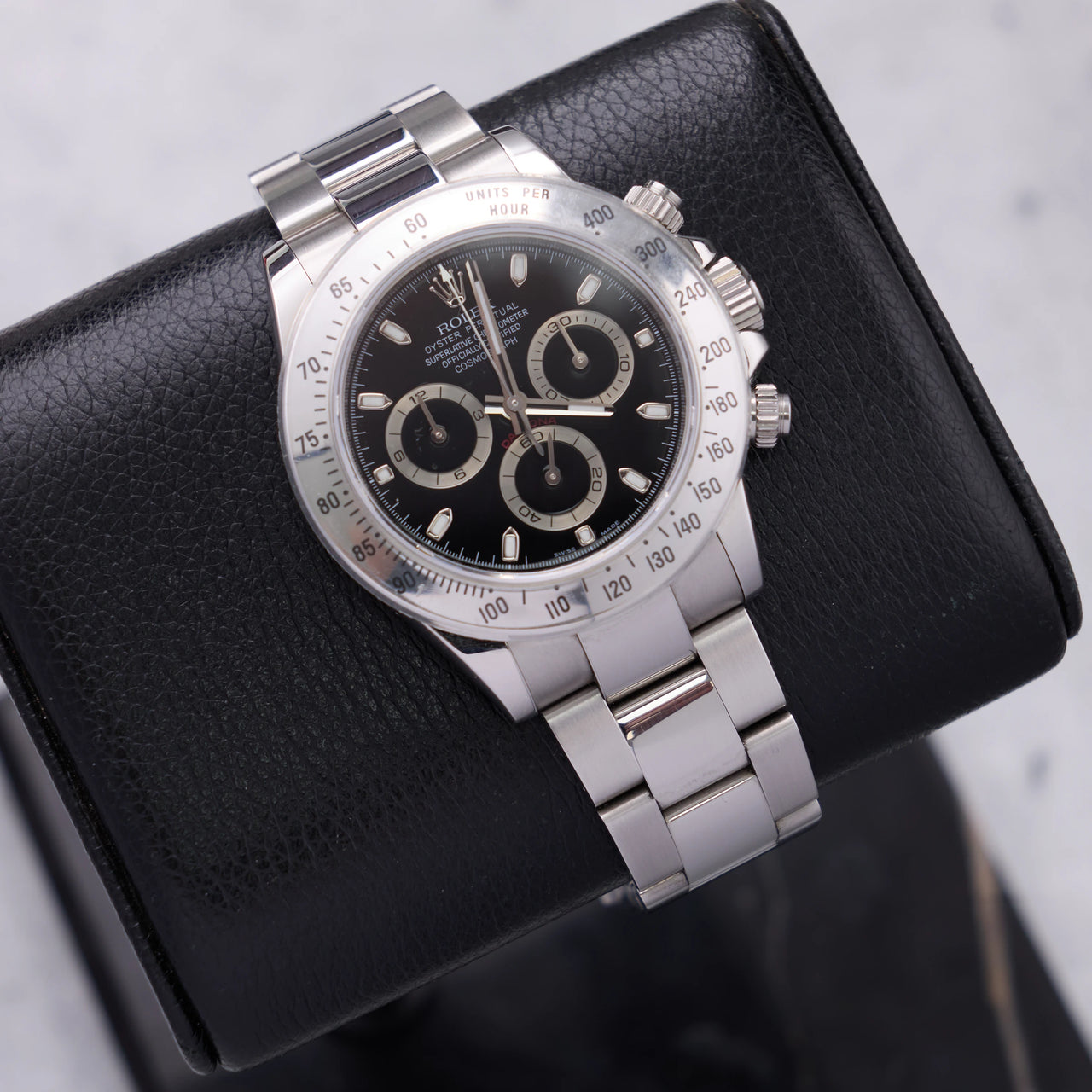 Rolex Daytona 40mm Stainless Steel Black Dial Tachymeter Bezel Oyster Bracelet (Ref 116520) - angled view on a black leather display stand