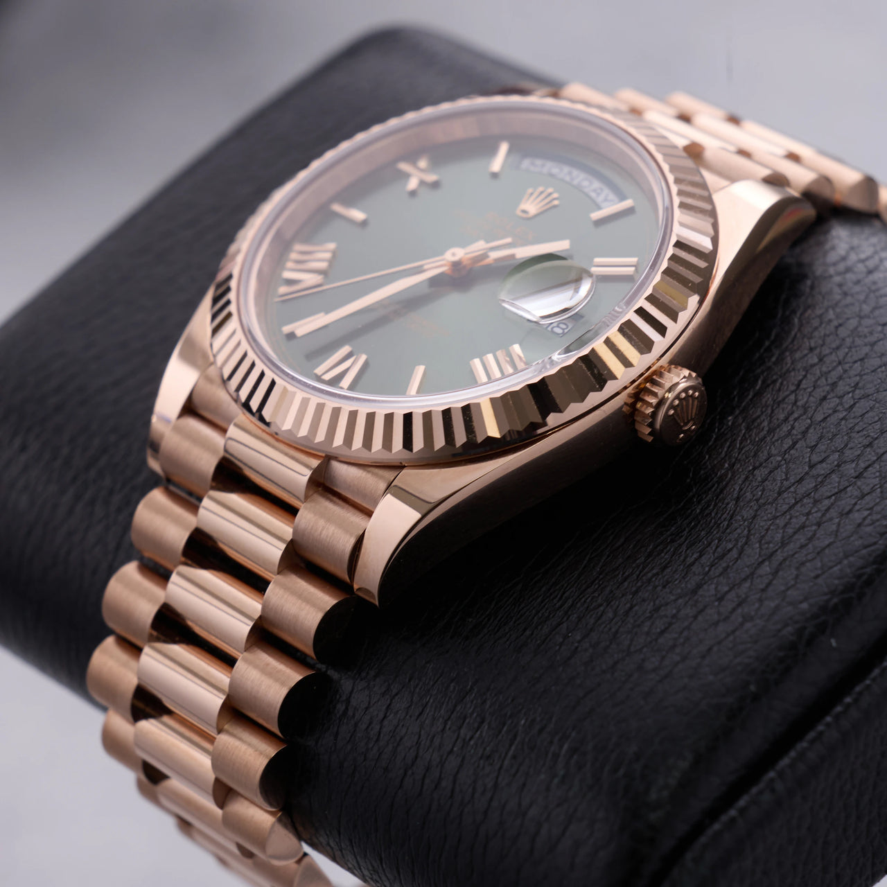 Rolex Day-Date 40mm 18K Everose Gold Olive Green Roman Dial Fluted Bezel President Bracelet (Ref 228235) - angled view of the dial, fluted bezel and crown on a display stand