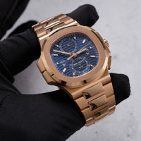 Thumbnail for Patek Philippe Nautilus Travel Time Chronograph 18K Rose Gold Blue Dial Ref 5990/1R-001 - angled dial view held in hand