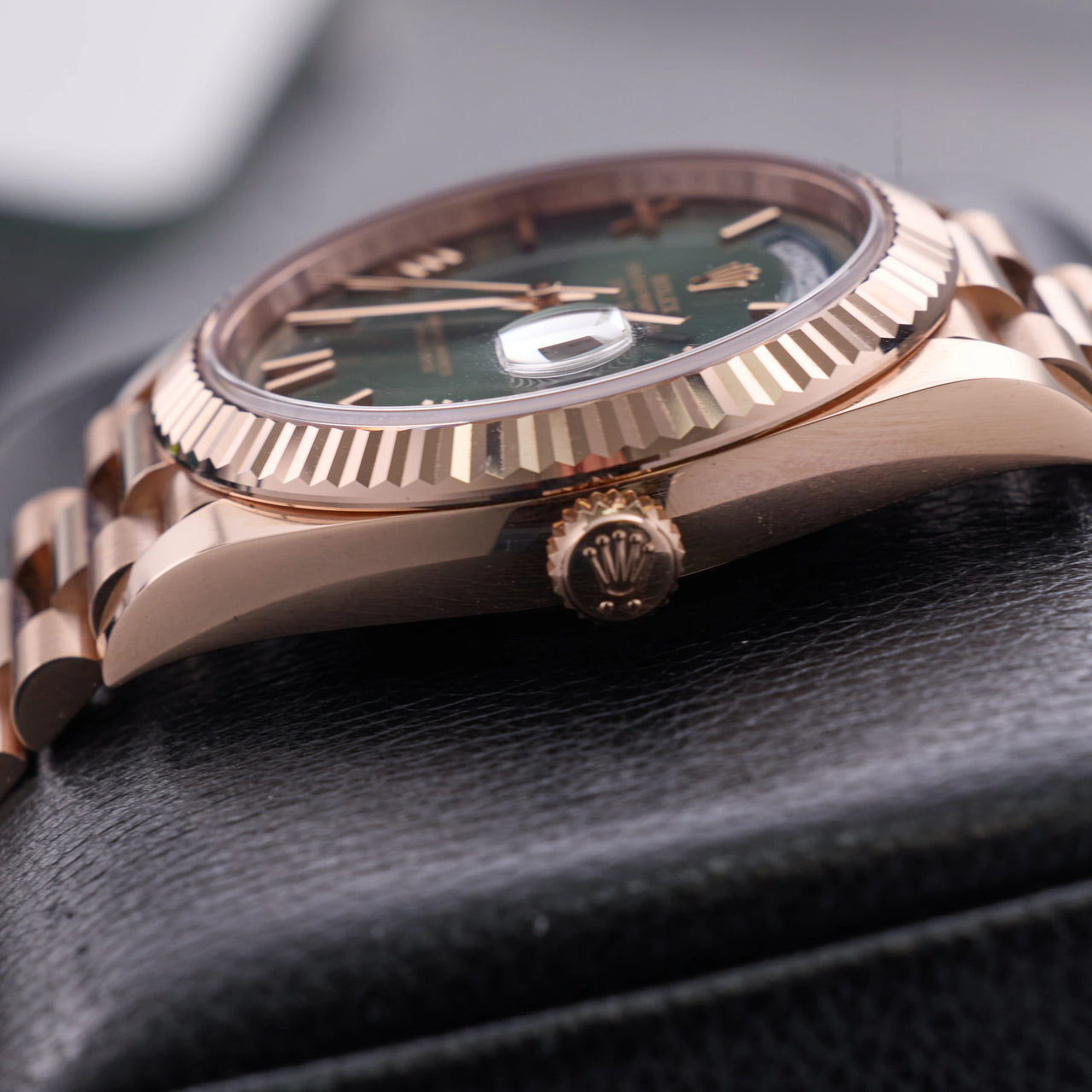 Rolex Day-Date 40mm 18K Everose Gold Olive Green Roman Dial Fluted Bezel President Bracelet (Ref 228235) - crown-side profile with the Rolex crown on a display stand
